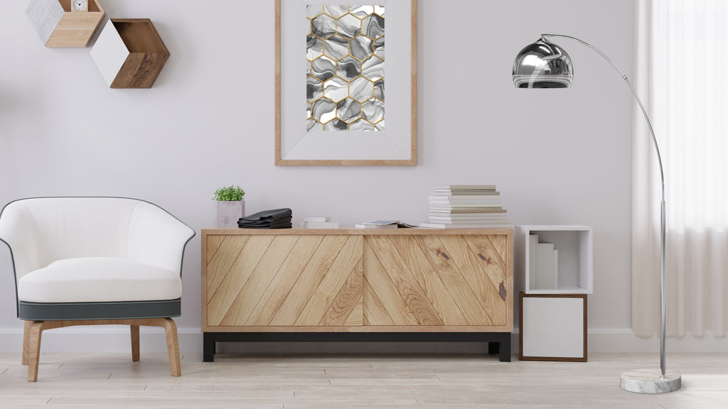 A wooden sideboard in front a white wall, surrounded by a white sofa chair and a silver floor lamp